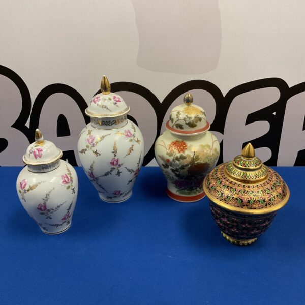 Four antique Japanese ginger jars on a blue surface.