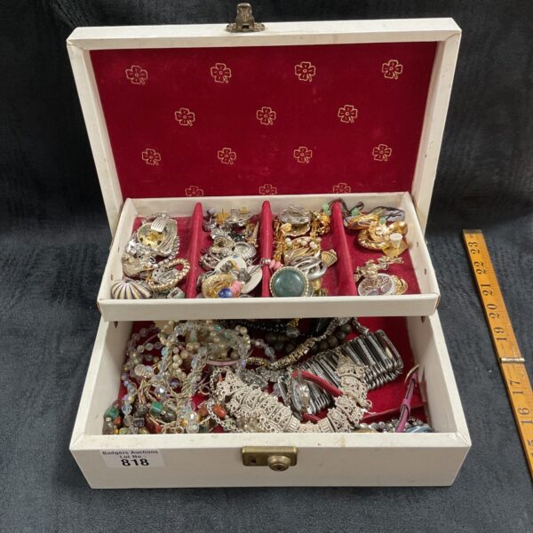 Vintage jewellery box overflowing with colourful costume jewellery pieces.