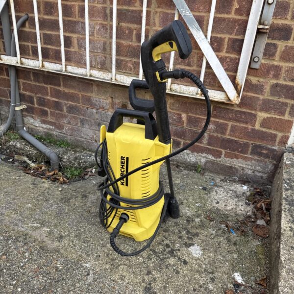 Yellow Karcher pressure washer with hose and handle.