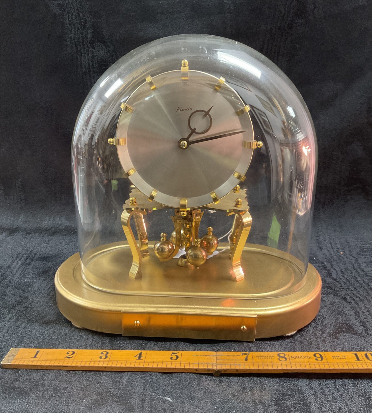 Vintage Kundo anniversary clock with glass dome and brass pendulum.