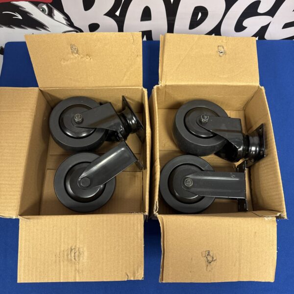 Four new large black castor wheels inside a cardboard box.