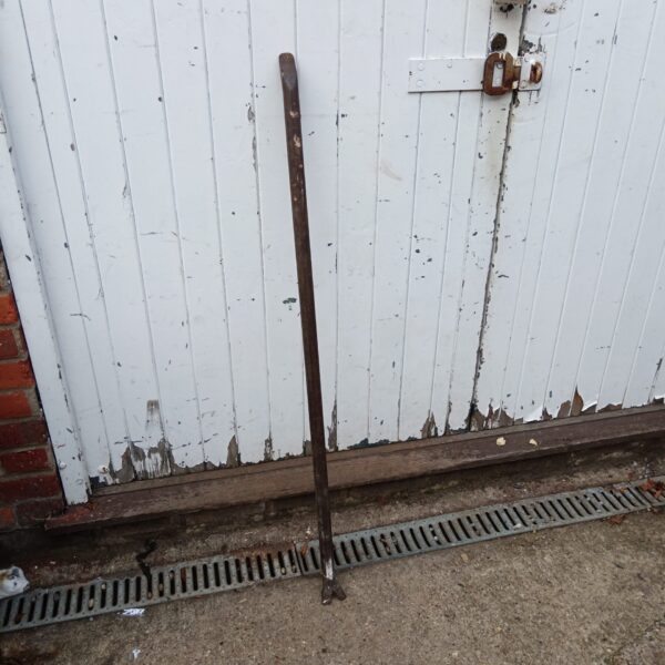 Large iron crowbar leaning against a white wall.