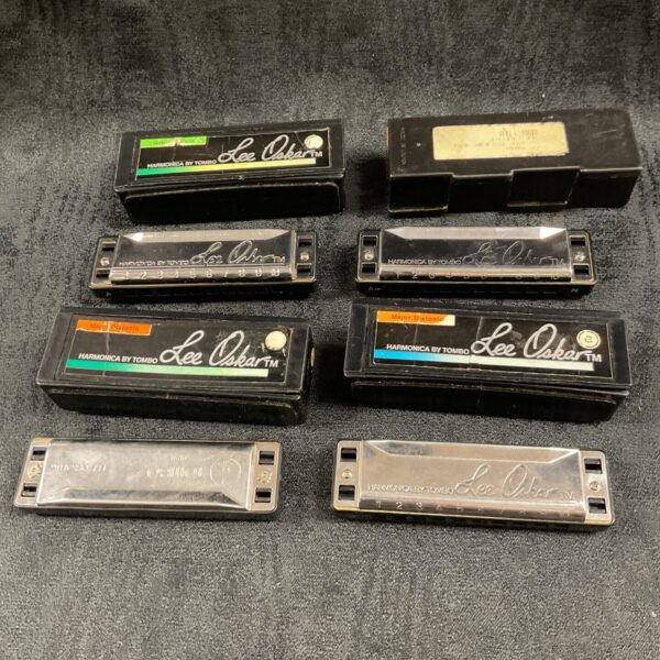 Vintage Lee Oskar harmonica collection on a wooden surface.