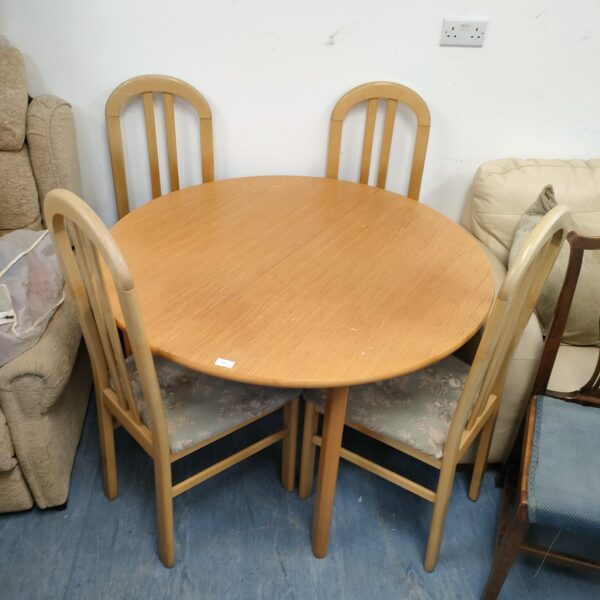 Light oak dining set with four chairs in a home setting.