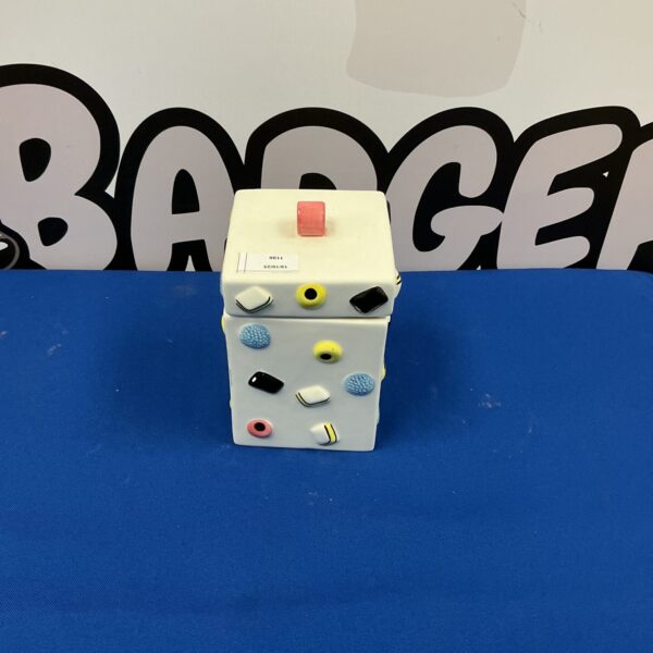 Colourful vintage Liquorice Allsorts cookie jar on a dark background.