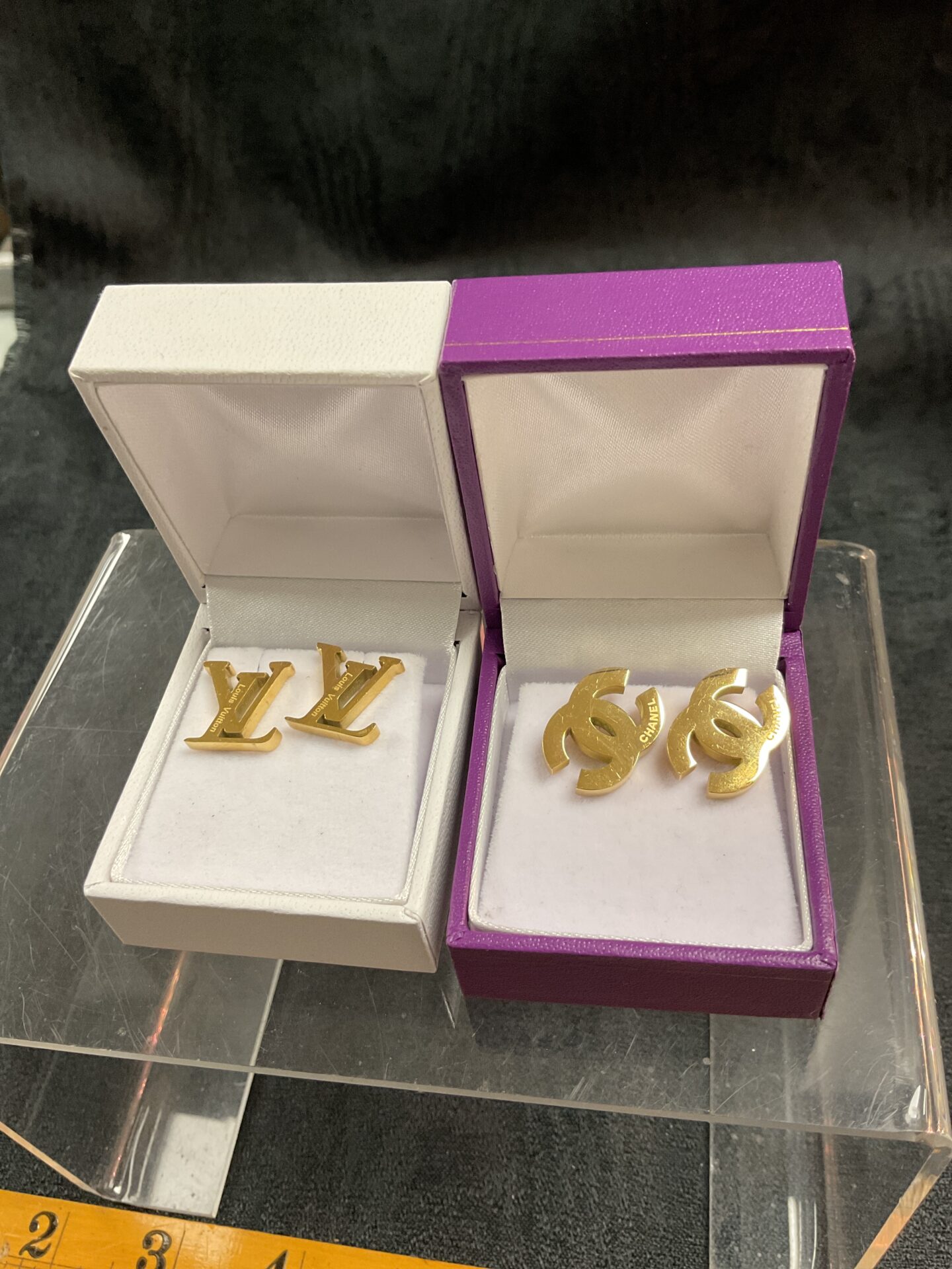 New designer stud earrings in packaging, featuring LV and CC logos.