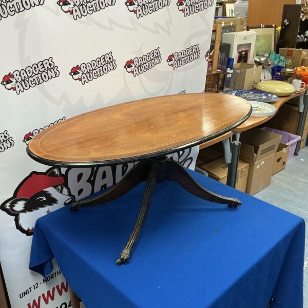 Vintage mahogany coffee table with oval shape and claw feet.