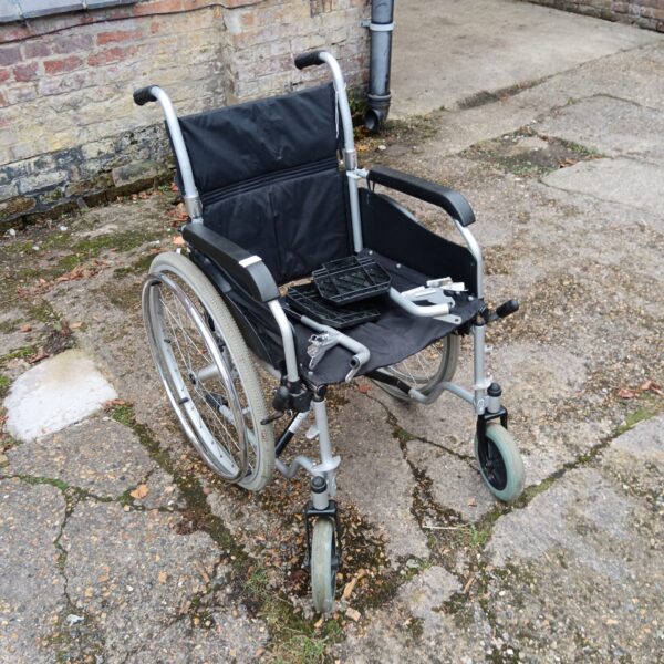 Side view of a used manual folding wheelchair with footrests.