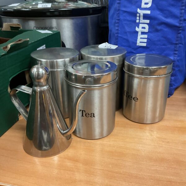 Stainless steel tea, coffee, and sugar pots set for kitchen storage.
