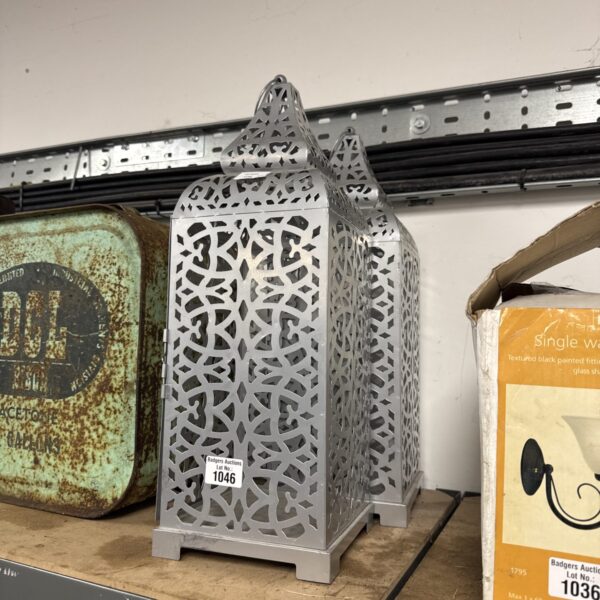 Intricate pierced metal candle lantern with decorative design.