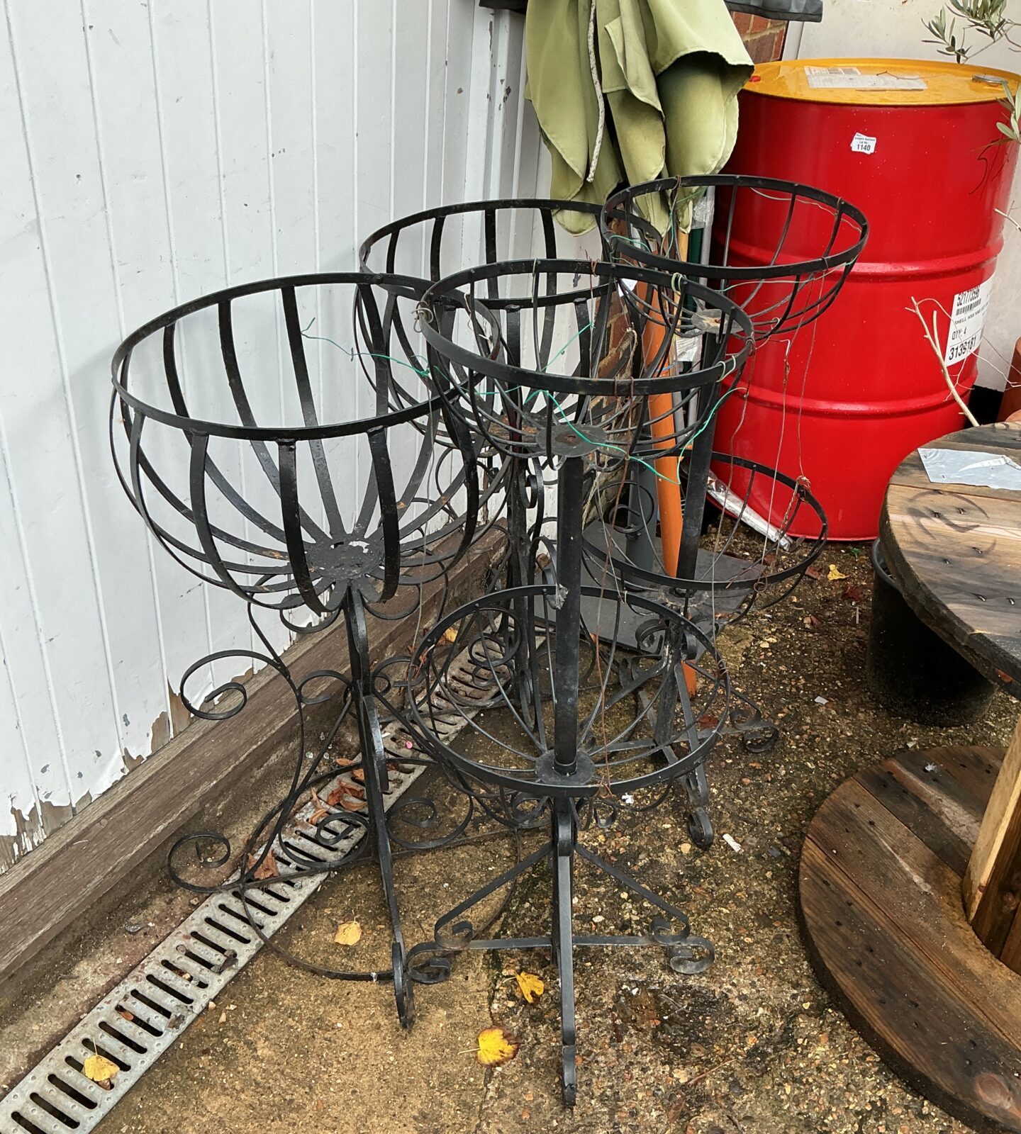 Set of four tiered metal garden basket plant stands for outdoor display.