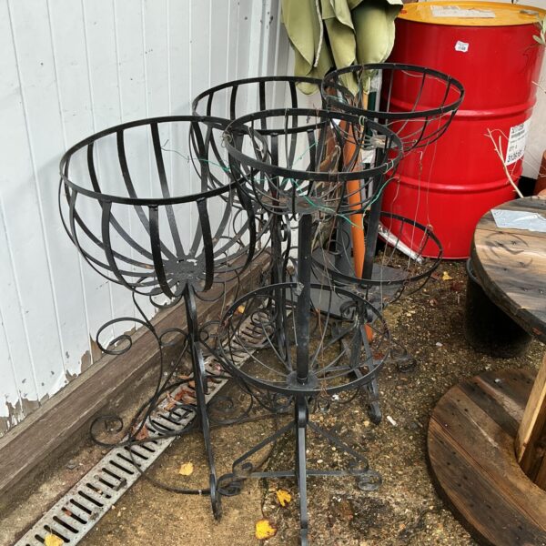 Set of four tiered metal garden basket plant stands for outdoor display.