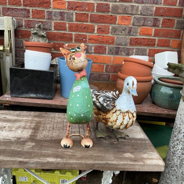 Colourful metal garden duck ornament in a garden setting.