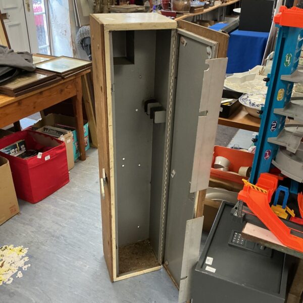 Vintage metal gun cabinet in a cluttered antique shop.