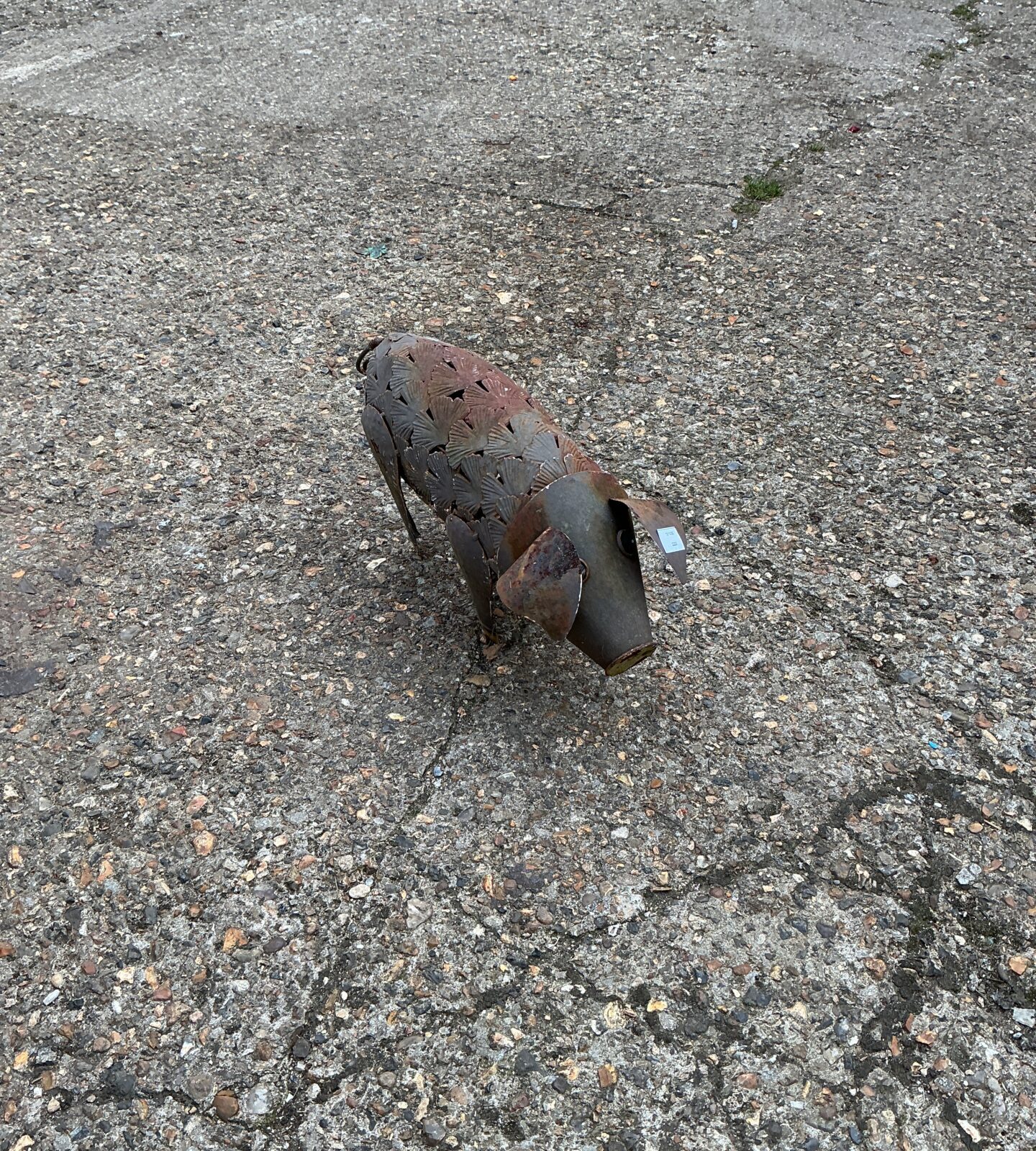 Rustic metal pig ornament in a garden setting.