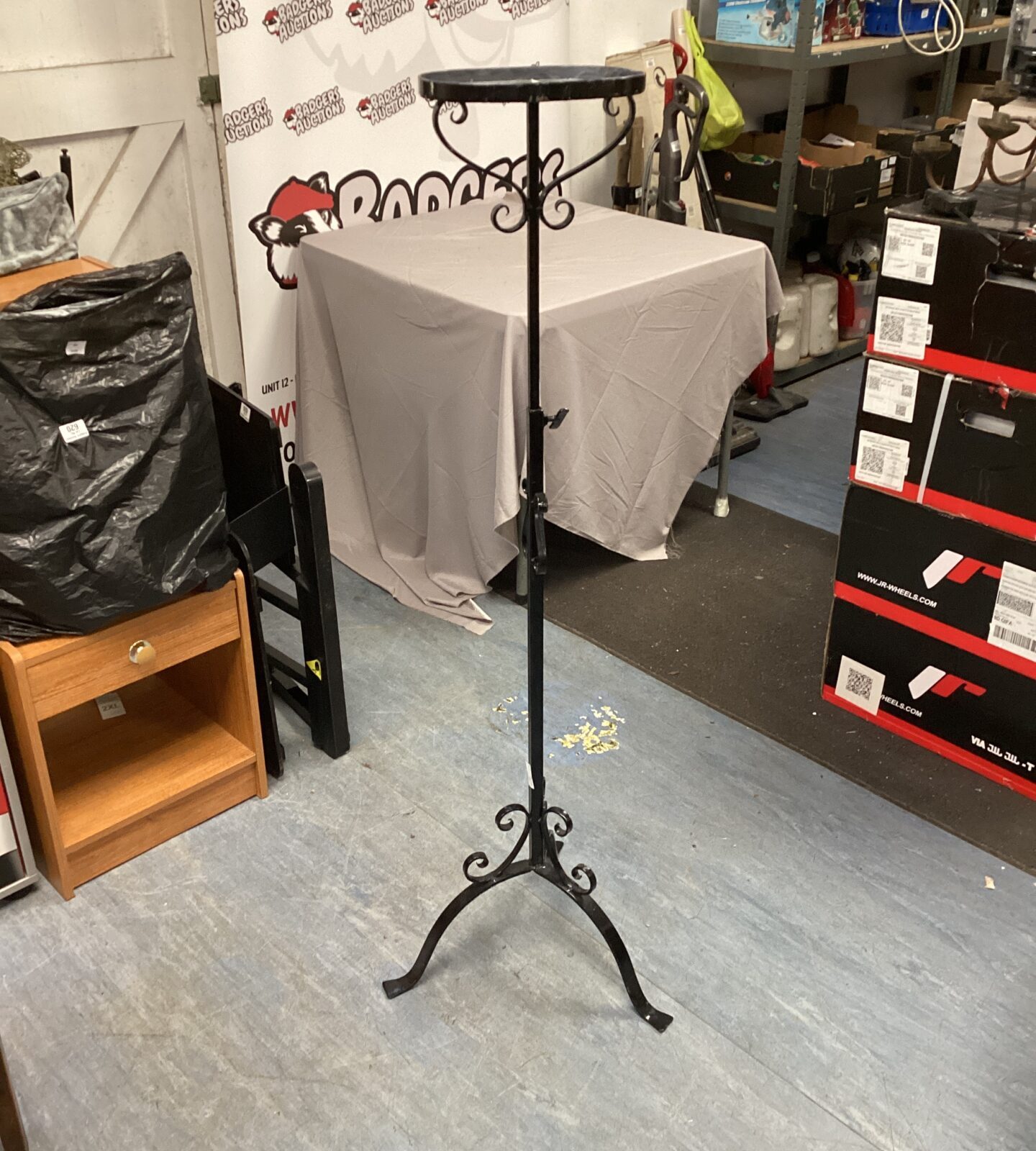 Adjustable metal pot stand with decorative wrought iron design.