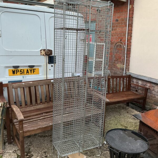 Industrial metal storage cage with wire mesh construction.