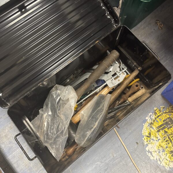 Metal tool storage box filled with assorted hand tools.