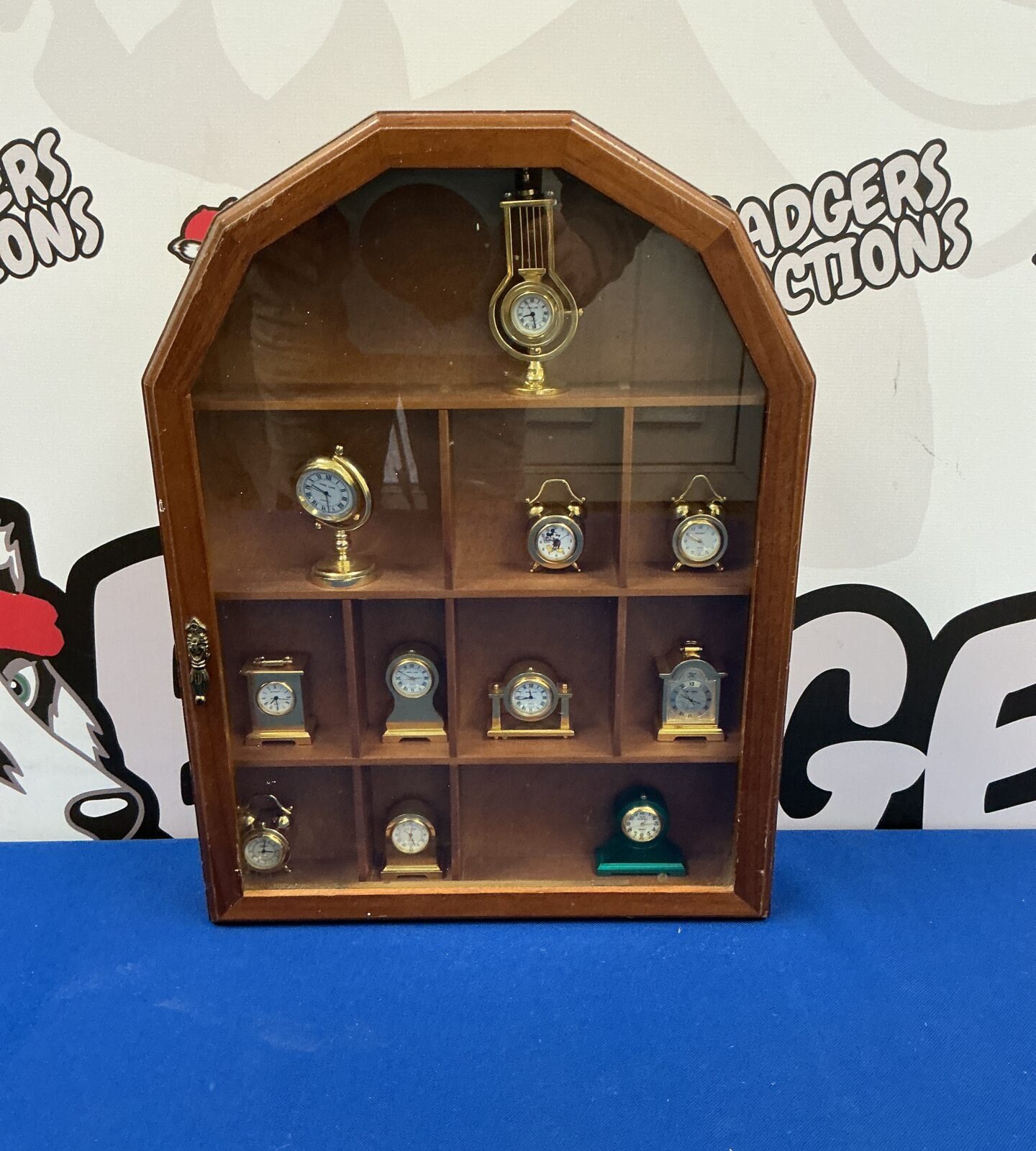 Vintage wooden display case with miniature clocks inside.