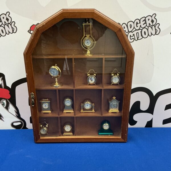 Vintage wooden display case with miniature clocks inside.