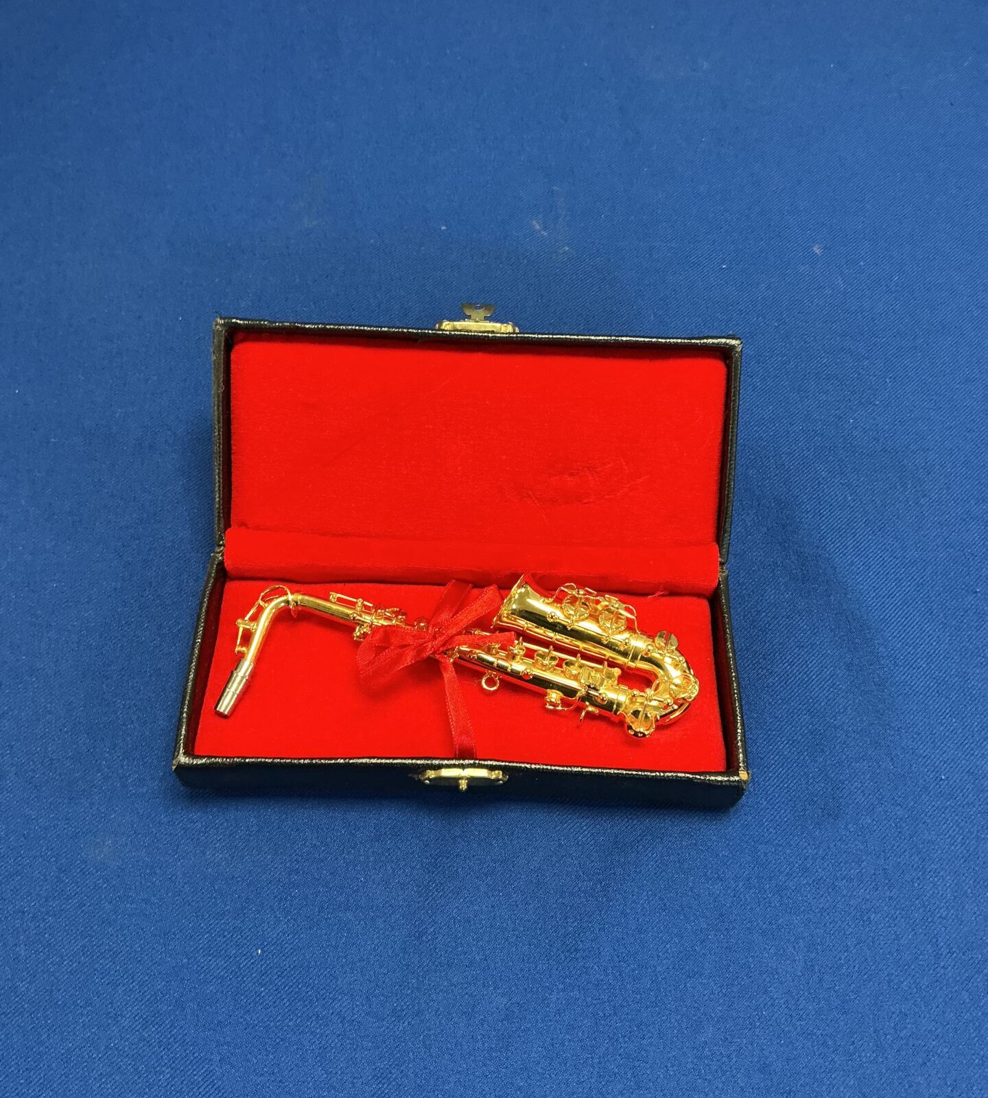 Detailed miniature metal saxophone in protective case.