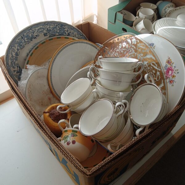 Mixed china collection in a cardboard box, including Royal Doulton and Wedgwood pieces.