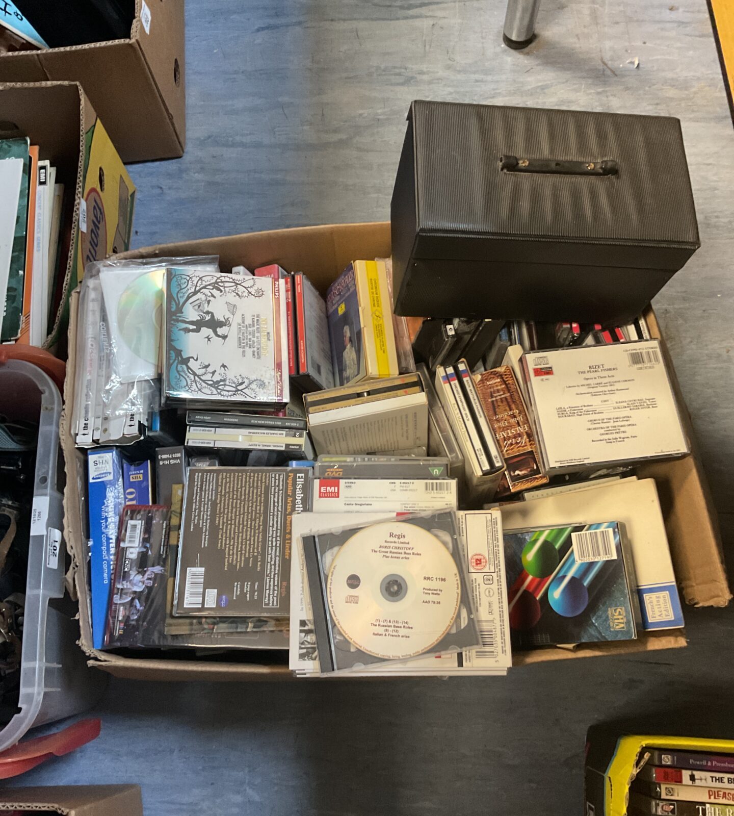 Overview of a mixed media lot including CDs, VHS tapes, and DVDs.