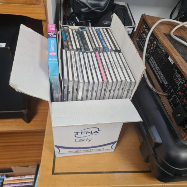 Mixed music CD lot in a cardboard box.