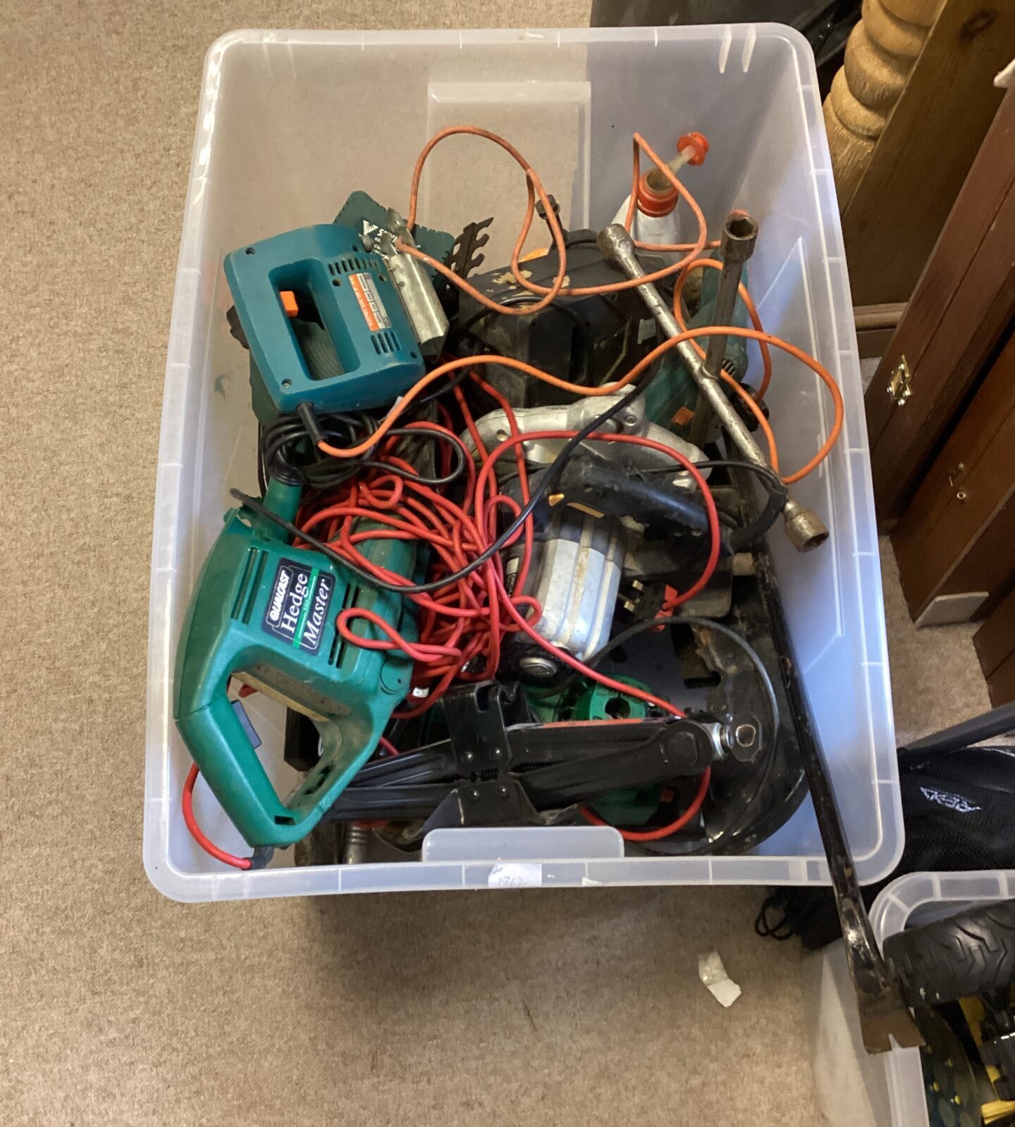 Crate filled with mixed power tools and hand tools.
