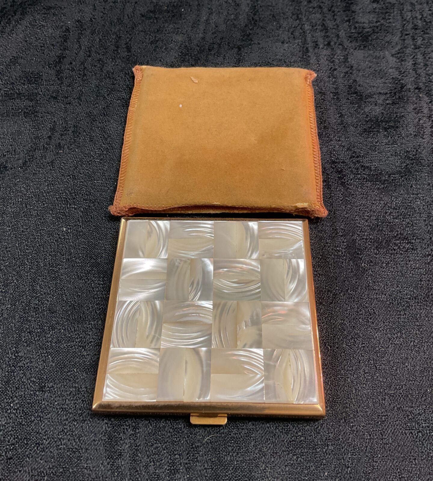 Open vintage mother of pearl cigarette case with brown lining.