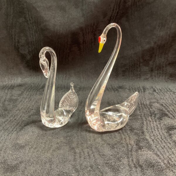 Elegant pair of vintage Murano glass swans on a dark background.