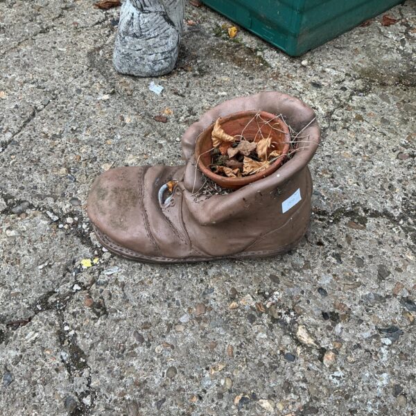 Rustic vintage leather boot planter in a garden setting.
