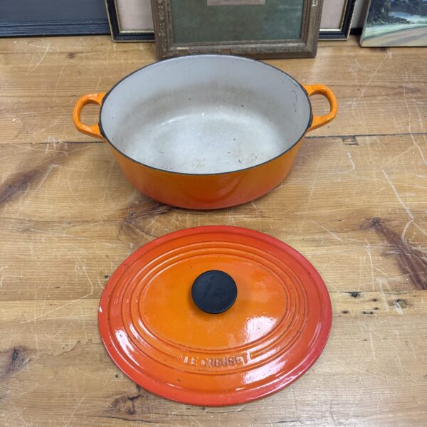 Vibrant orange Le Creuset crock pot, vintage enamel cookware.