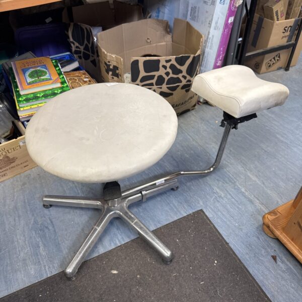 Adjustable height pedicure stool with footrest for salon use.