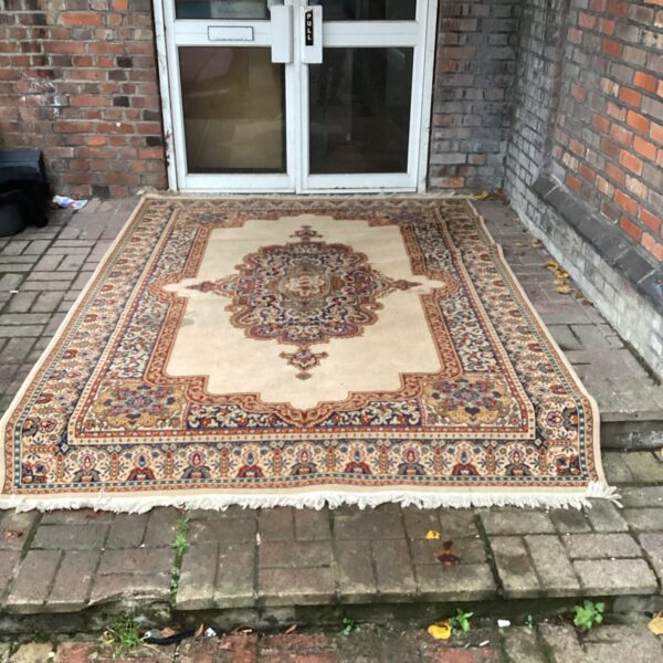 Vintage Persian rug with intricate floral patterns on a wooden floor.