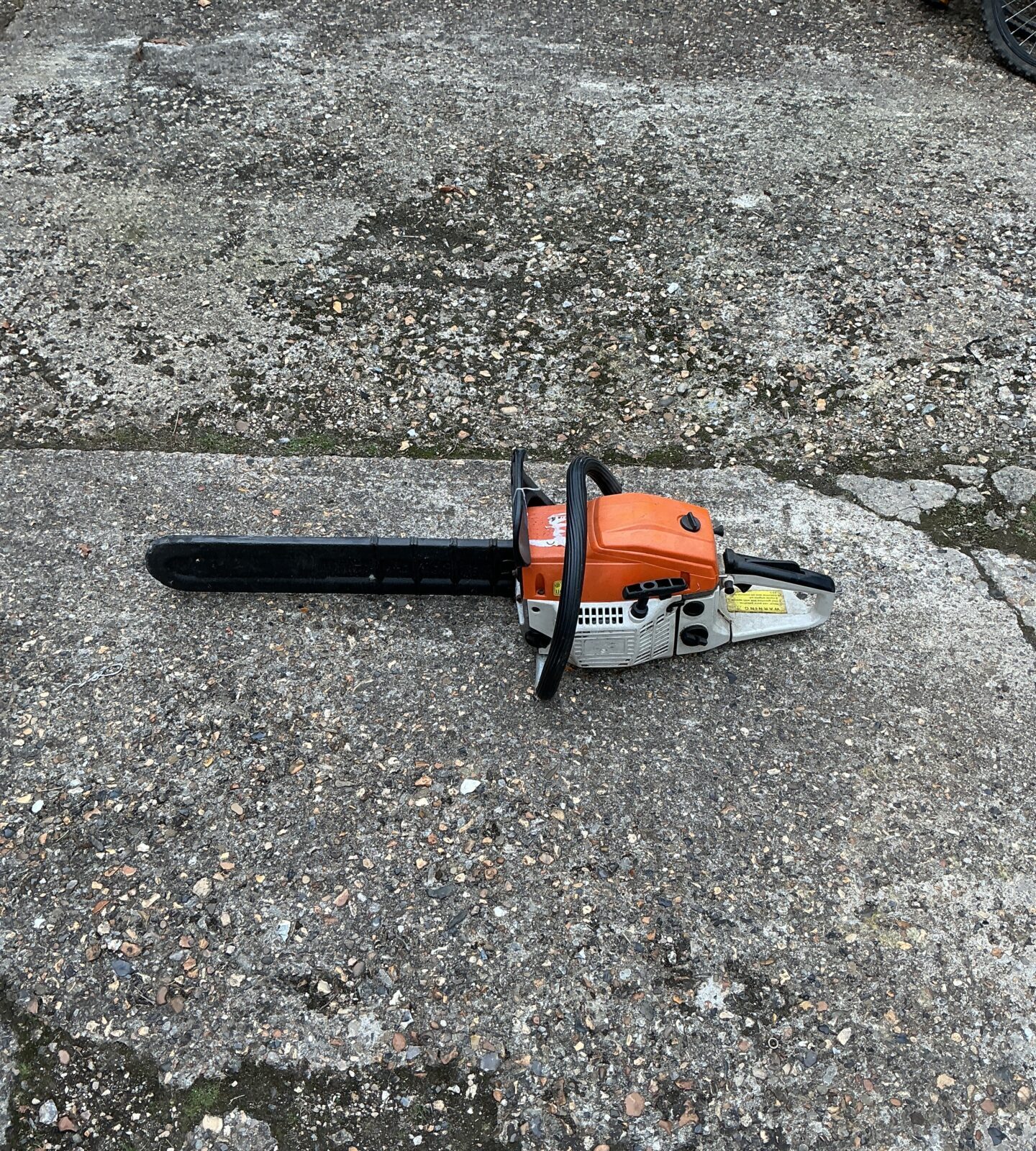 Front view of a used petrol chainsaw for garden and DIY tasks.