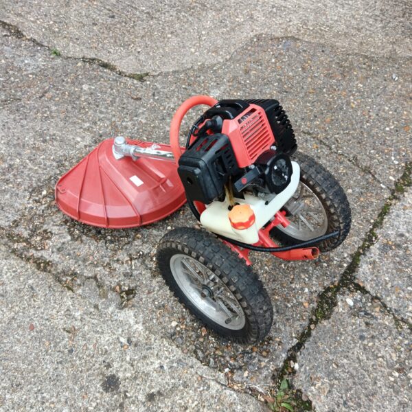Used petrol grass strimmer with wheels for garden maintenance.