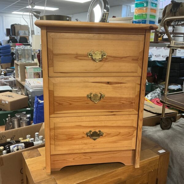 Vintage pine bedside cabinet with three drawers for bedroom storage.
