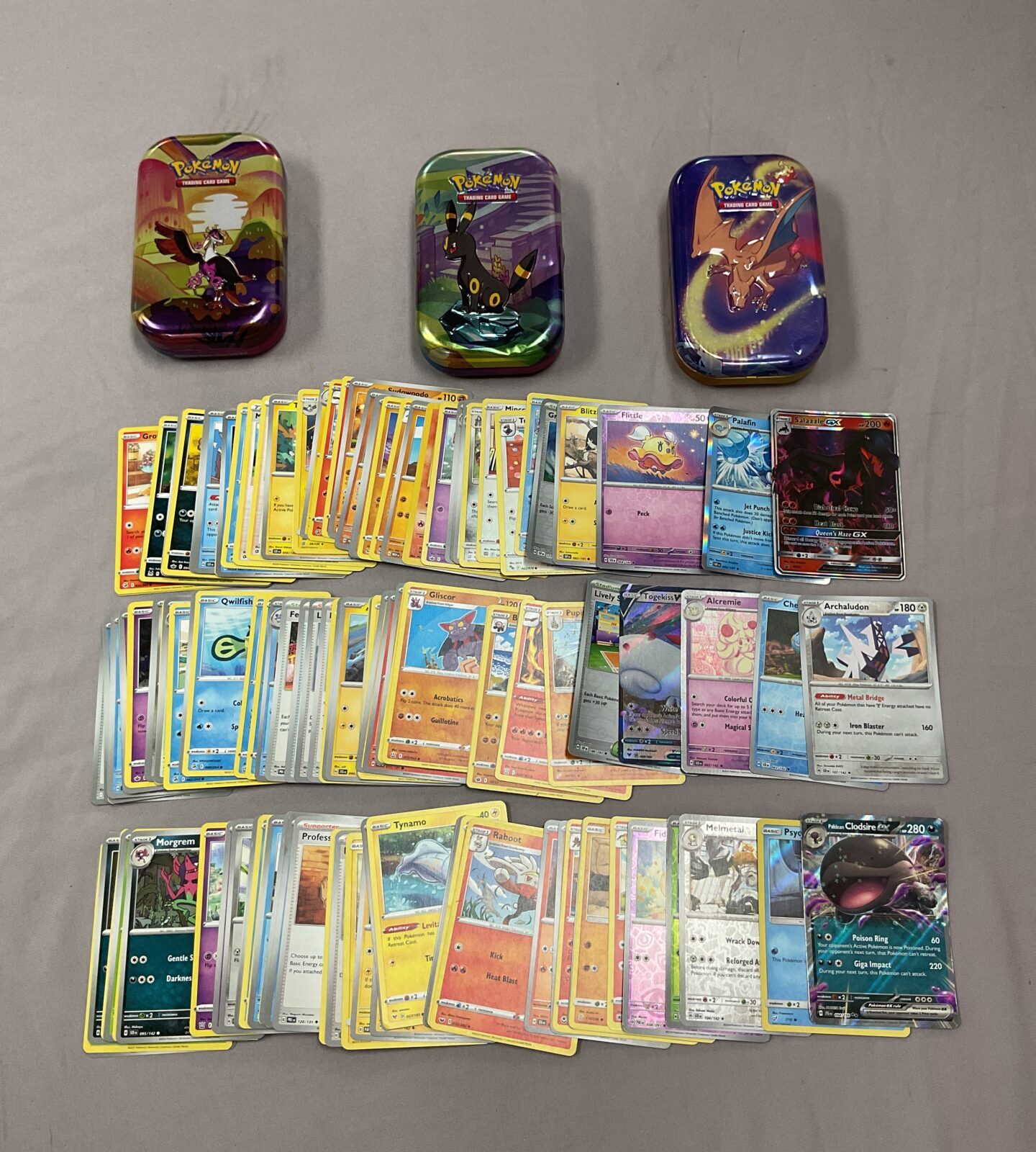 Pokemon card collection in tins with holographic cards visible.