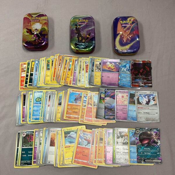 Pokemon card collection in tins with holographic cards visible.