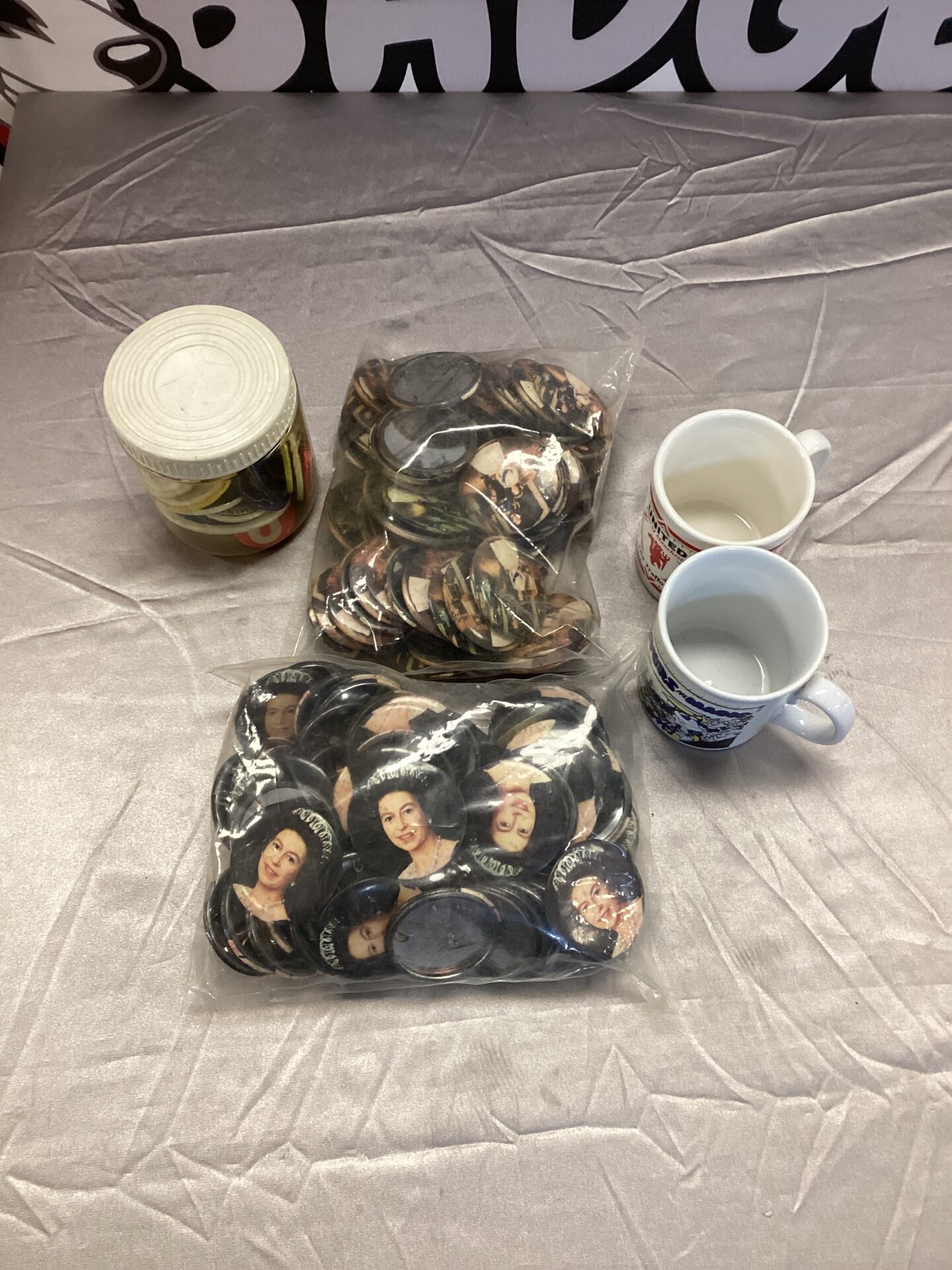 Queen Elizabeth badges and football mugs in a collectables lot.