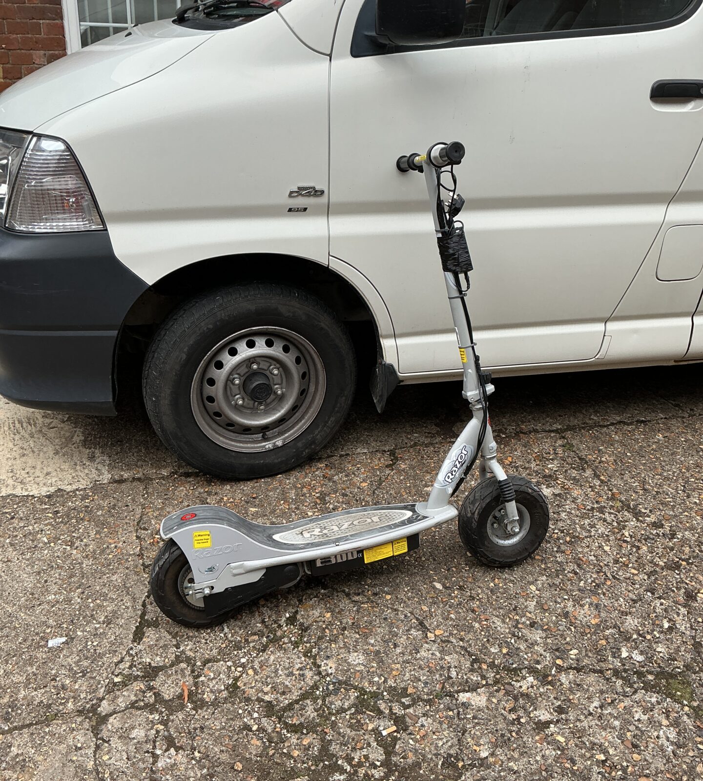 Side view of a blue Razor electric scooter with charger.