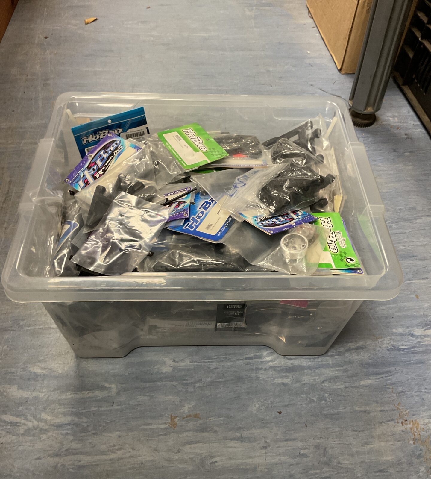 Mixed lot of RC model parts and accessories in a storage box.