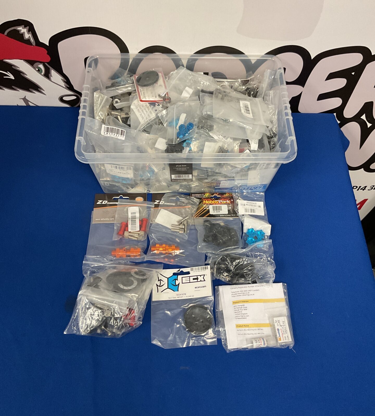 Assorted RC model parts and hobby accessories in a plastic storage box.