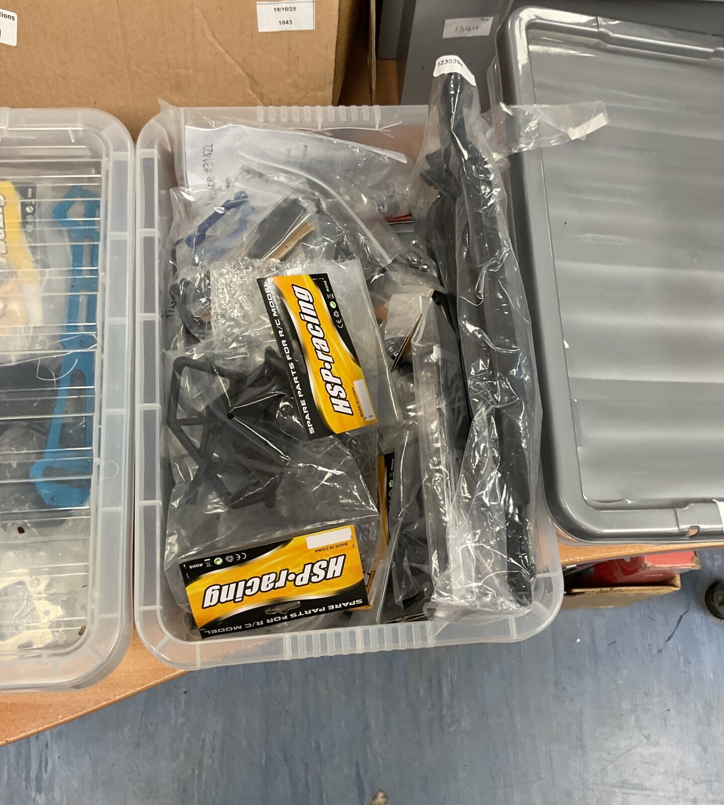 Assorted RC model parts and accessories in a storage box.