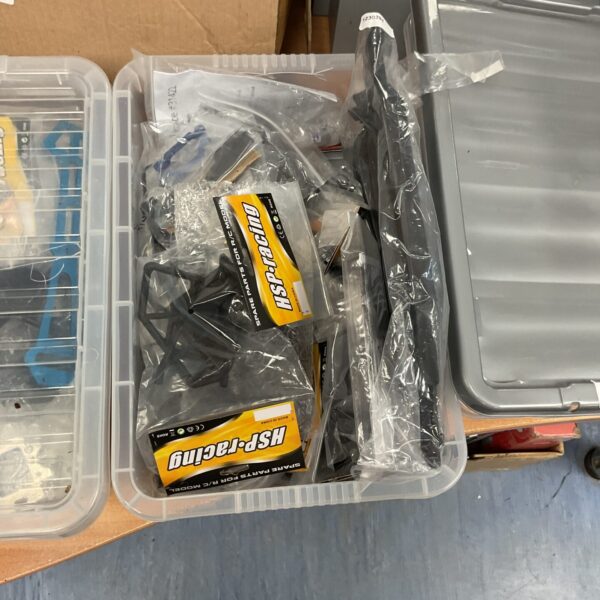 Assorted RC model parts and accessories in a storage box.