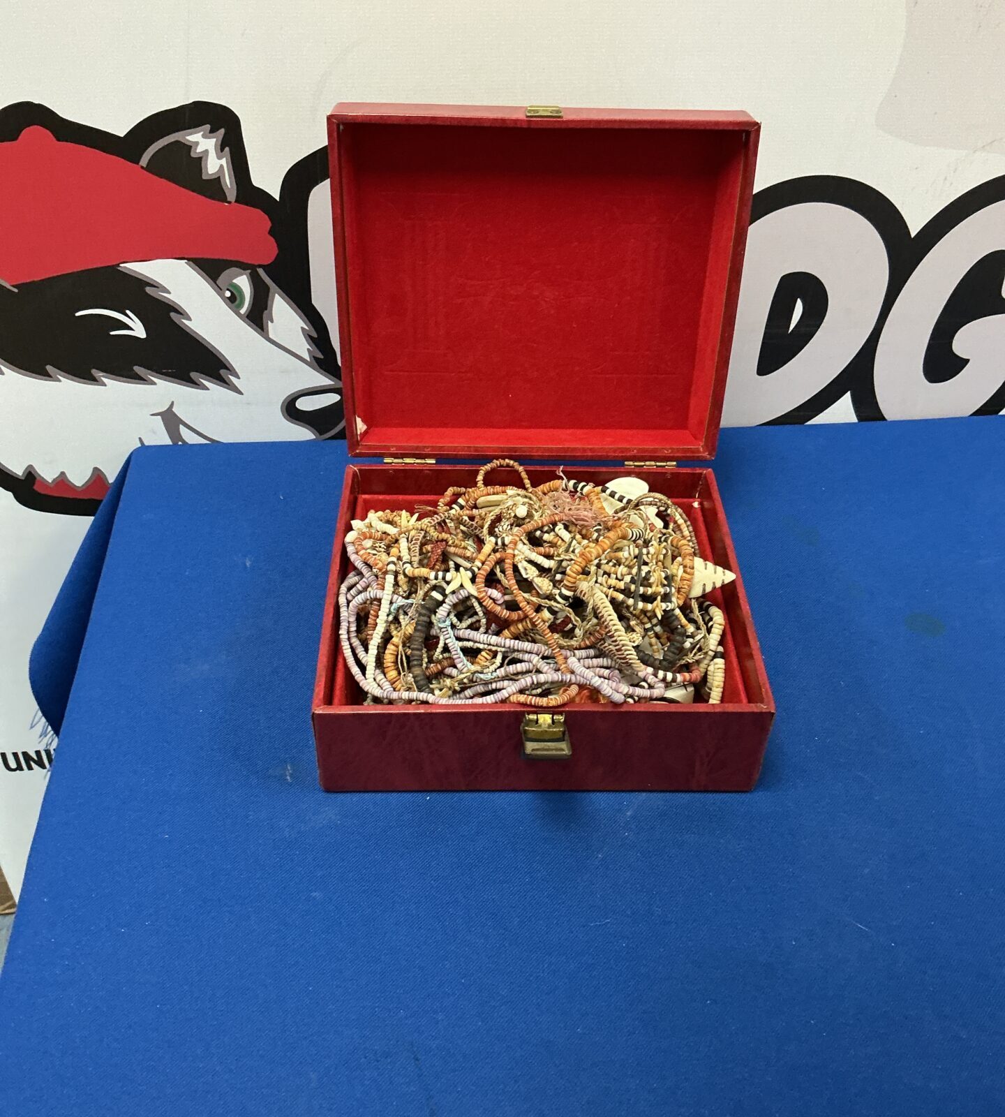 Open red leather jewellery box filled with colourful beaded necklaces.