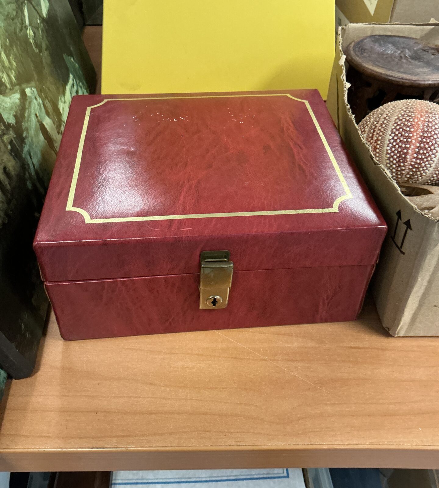 Side view of a red leather jewellery box with clasp closed.