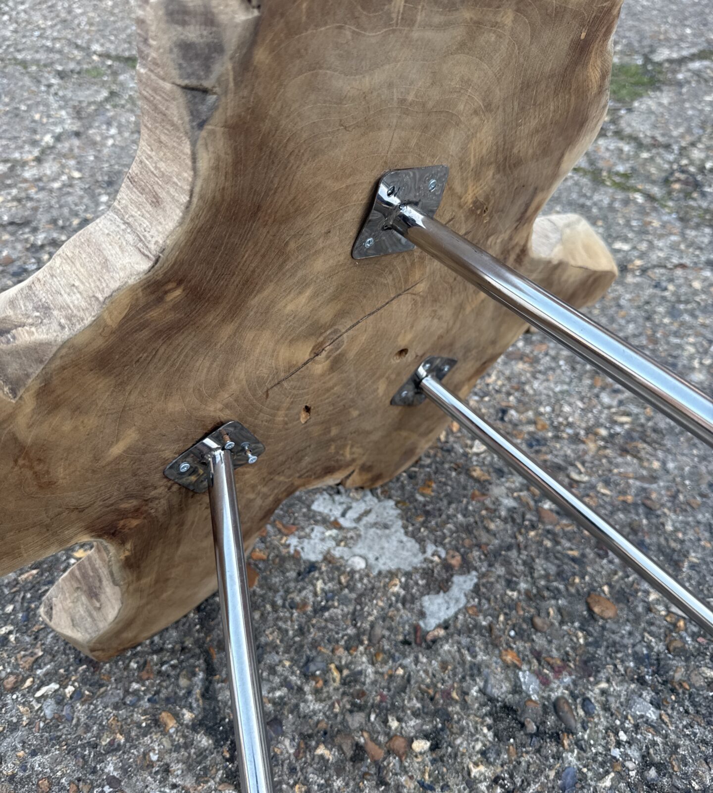 Rustic wood side table with metal legs in a garden setting.