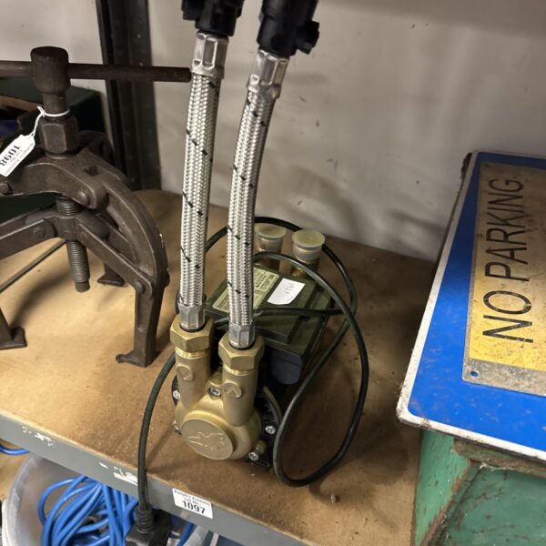 Side view of a used Salamander shower pump with flexible connections.